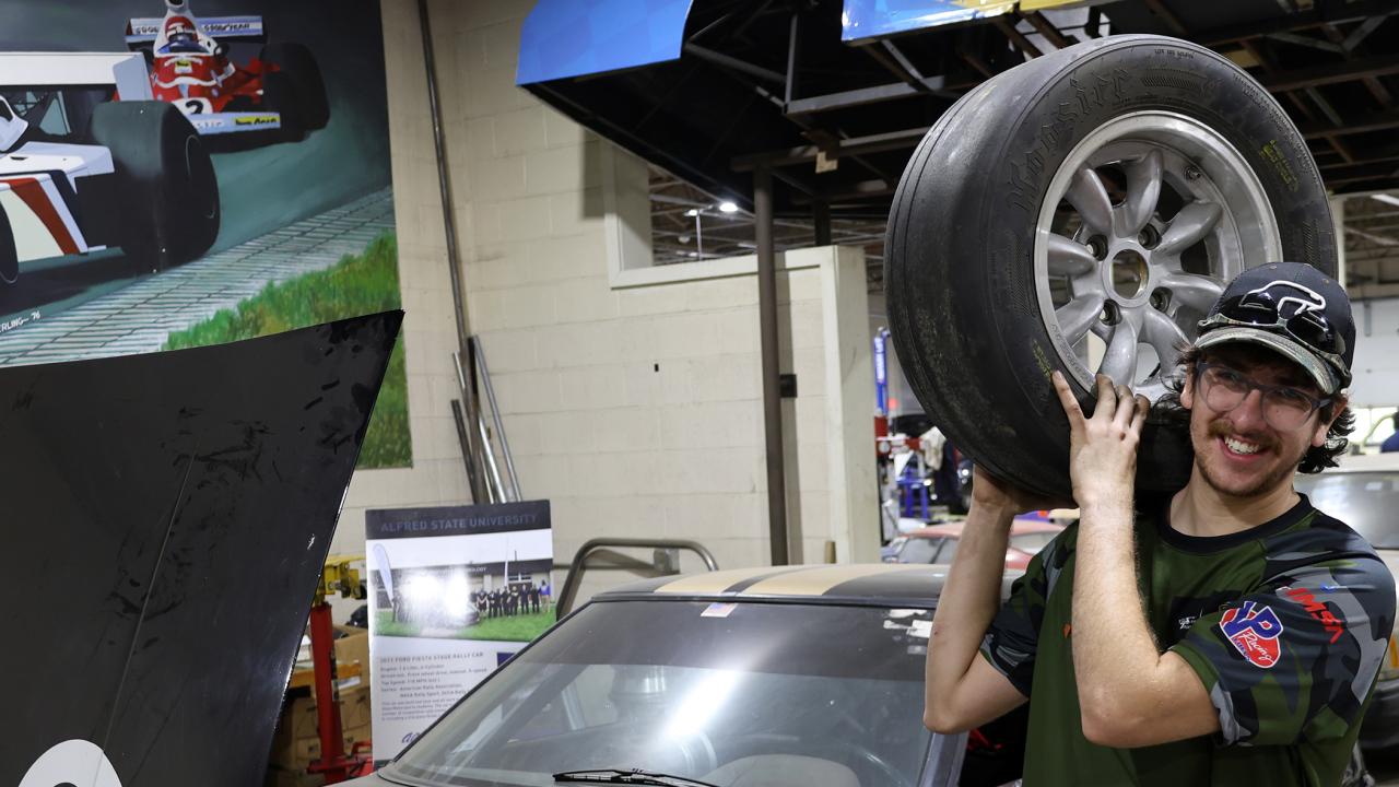 Quinn Scanlon holds a tire in the motorsports lab