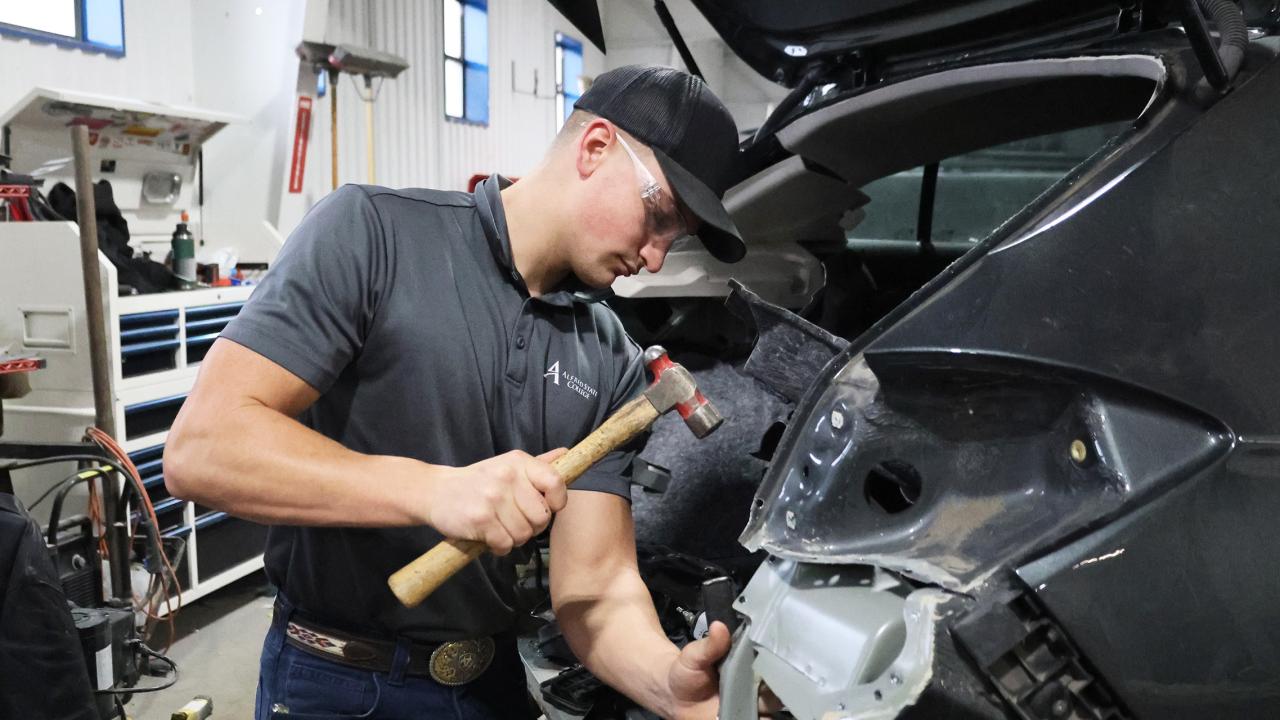 student works on a wrecked car