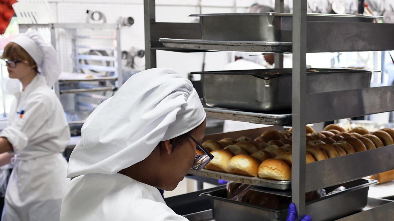 student wheels a tray of buns
