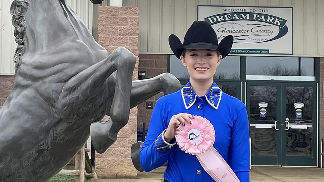 student displays ribbon outside arena