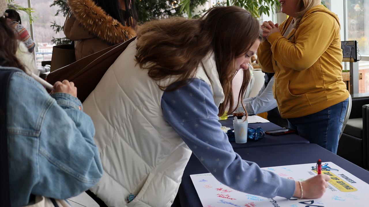 student signs a thank you card