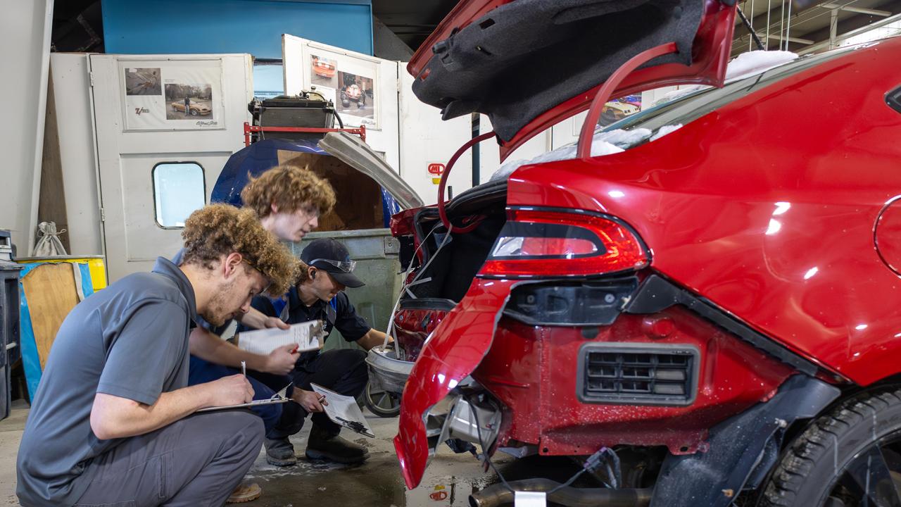students assess a car for damage